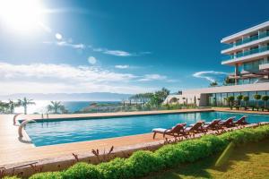 a swimming pool with chairs and the ocean in the background at ON'LIVE HOTEL in Çeşme