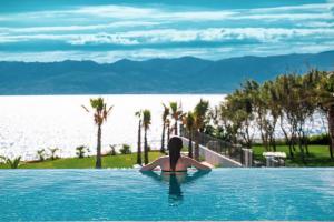 a woman sitting in a swimming pool looking at the water at ON'LIVE HOTEL in Çeşme