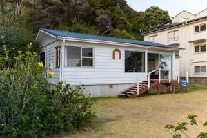 a white house with a staircase in a yard at Dream View Waterfront Paihia in Paihia