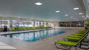 a large swimming pool with green chairs in a building at Holiday Inn Cleveland - South Independence, an IHG Hotel in Independence