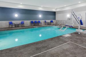 a swimming pool with blue chairs in a room at Holiday Inn Express & Suites - Rice Lake, an IHG Hotel in Rice Lake