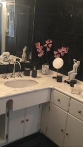 baño con lavabo, espejo y flores rosas en B&B La Casa di Isabella Loreto, en Loreto