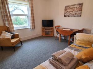 Habitación con cama, mesa y TV. en Summerhill Apartments en Shanklin