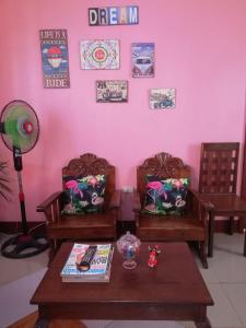 a room with two chairs and a table and a pink wall at Agimats Crib Palawan in Puerto Princesa City