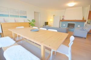 a living room with a wooden table and white chairs at Point Break in Oostduinkerke