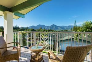 a balcony with chairs and a table with a view of the mountains at Villas of Kamalii 47 home in Princeville