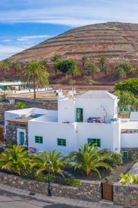 a white house with palm trees in front of a hill at Timanfaya Casa Rural in Yaiza