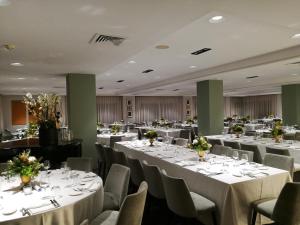 um salão de banquetes com mesas e cadeiras brancas em Hotel Marad em Torre del Greco