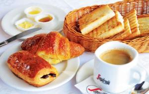 a table with a plate of pastries and a cup of coffee at Latanier Beach Hotel in Grand-Baie