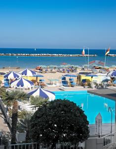 a swimming pool with umbrellas and a beach at Hotel Italia in Bellaria-Igea Marina