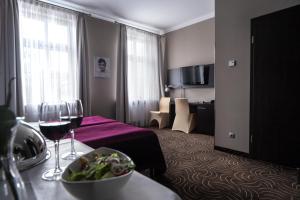 ラチブシュにあるHotel Raciborのテーブルとワイン2杯が備わるホテルルームです。