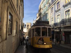 un tranvía amarillo conduciendo por una calle de la ciudad en Draft Hostel & Rooms en Lisboa