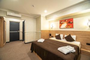 Una habitación de hotel con una cama con toallas. en Mildom City Hotel, en Almaty