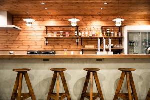 a bar with wooden walls and wooden stools at Ten to Ten Hostel in Sapporo