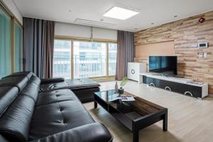 uma sala de estar com um sofá de couro preto e uma televisão em Home Fourest Residence Hotel Okpo em Geoje
