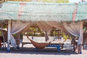 una hamaca y un banco bajo un techo de paja en Club Monet Beachfront Resort by Cocotel, en Zambales