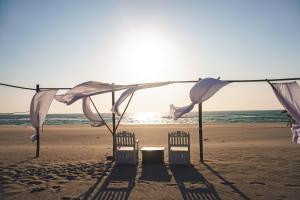 dos sillas en la playa bajo una sombrilla en Club Monet Beachfront Resort by Cocotel, en Zambales