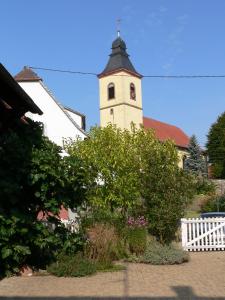 una chiesa con una torre con un orologio sopra di Familiensuite, zwei Zimmer, Mitbenutzung von Küche und Bad a Rott