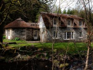 an old stone house with a thatched roof at Forget Me Not Holiday Cottage in Dalmellington