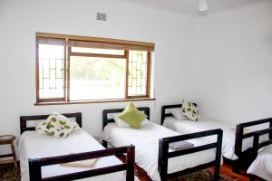 three beds in a room with a window at Norfolkden Beachhouse in Hermanus