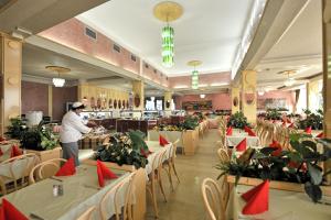 a chef preparing food in a restaurant with tables and chairs at Hotel Istra Plava Laguna in Poreč