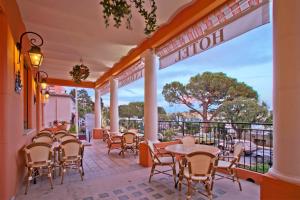 a patio with tables and chairs on a balcony at Hotel De La Darse in Villefranche-sur-Mer