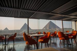 una cafetería con mesas, sillas y pirámides en el fondo en Marvel Stone Hotel, en El Cairo