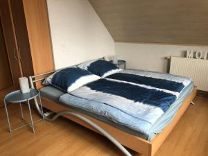 Bett mit blauer Bettwäsche und Kissen in einem Zimmer in der Unterkunft Haus Kleewiese in Ulmen