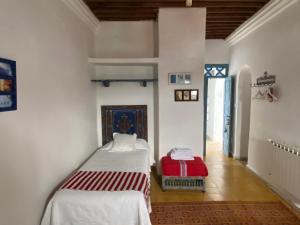 Cette chambre comprend 2 lits et une valise rouge. dans l'établissement Casa Perleta, à Chefchaouen