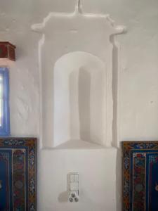 una parete bianca con una mensola in una stanza di Casa Perleta a Chefchaouen