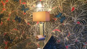 a lamp on a table in a room with a wallpaper at Hotel Relais Du Postillon in Antibes