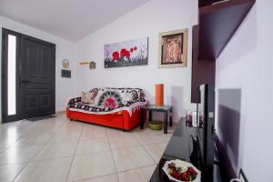 a living room with a red couch and a tv at House Rita Marzamemi in Marzamemi