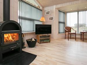 een woonkamer met een open haard en een televisie bij 7 person holiday home in Hj rring in Hjørring