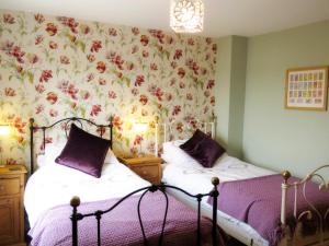 two beds in a bedroom with a floral wallpaper at The Cloisters in York