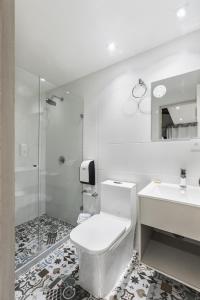 a white bathroom with a toilet and a sink at Casa Hotel Solare de la 70 in Medellín