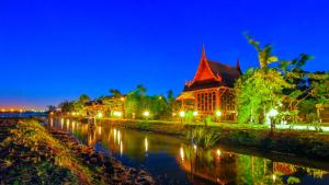 a building next to a river at night at Pludhaya Resort & Spa in Phra Nakhon Si Ayutthaya