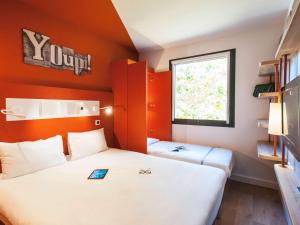 2 letti in una piccola camera con pareti arancioni di ibis budget Château-Thierry a Essômes-sur-Marne