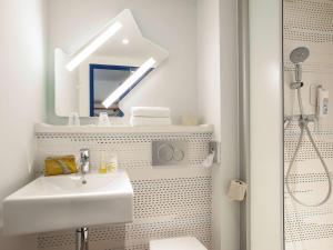ein weißes Badezimmer mit einem Waschbecken und einem Spiegel in der Unterkunft ibis budget Château-Thierry in Essômes-sur-Marne
