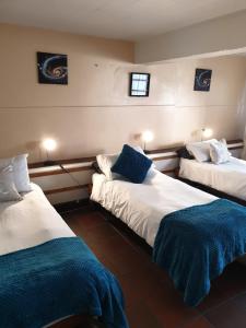 a room with two beds with blue and white sheets at Zebra Crossing Backpacker in Cape Town