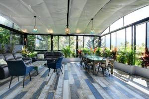 un salón acristalado con mesa, sillas y plantas en International House Co-Living, en Medellín