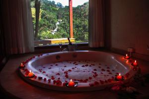eine Badewanne mit Kerzen in einem Zimmer mit Fenster in der Unterkunft Pousada Espelho Dagua in Gonçalves