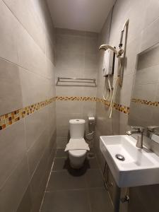 a bathroom with a white toilet and a sink at De Chukai Hotel in Kampong Kemaman