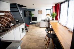 eine Küche und ein Wohnzimmer mit einer Theke und Stühlen in der Unterkunft Le cottage du clos des Forges in Saint-Leu-dʼEsserent