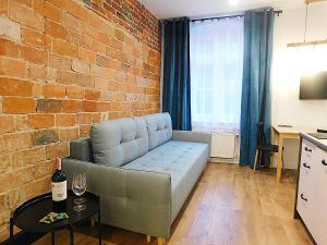 - un salon avec un canapé et un mur en briques dans l'établissement Apartament BAJ No.2, à Toruń