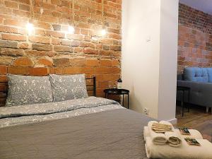 - une chambre avec un lit et un mur en briques dans l'établissement Apartament BAJ No.2, à Toruń