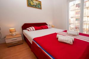 a bedroom with a bed with a red blanket and a window at Apartment Ajdukovic in Vodice