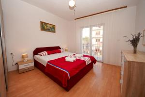 een slaapkamer met een bed met een rode en witte deken bij Apartment Ajdukovic in Vodice