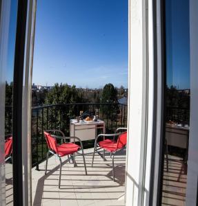 Un balcón con sillas rojas y una mesa con vistas. en La Terrasse du Colombier, en Limoges