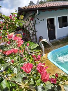 a pool with pink flowers in front of a house at Pousada Lira Haus in Pomerode