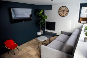 a living room with a couch and a clock on the wall at Le cottage du clos des Forges in Saint-Leu-dʼEsserent